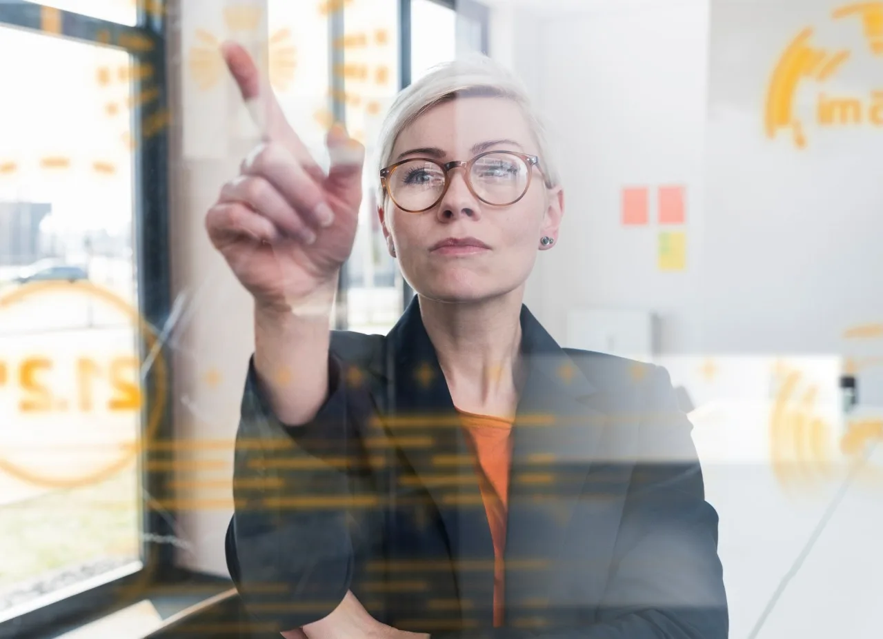 Businesswoman touching glass wall with data in office